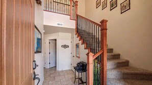 A staircase with wooden railings and a carpeted floor leading to a room with a piano.