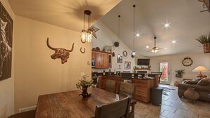 A spacious kitchen with wooden cabinets, a dining area with a wooden table and chairs, and a living area with a sofa and a lamp.