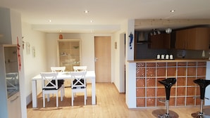 Una cocina compacta con barra, piso de madera y muebles blancos.