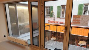A hotel entrance with a glass door, a bench outside, and a view of the restaurant across the street. - Green Marmot Capsule Hotel Zurich (Zürich)