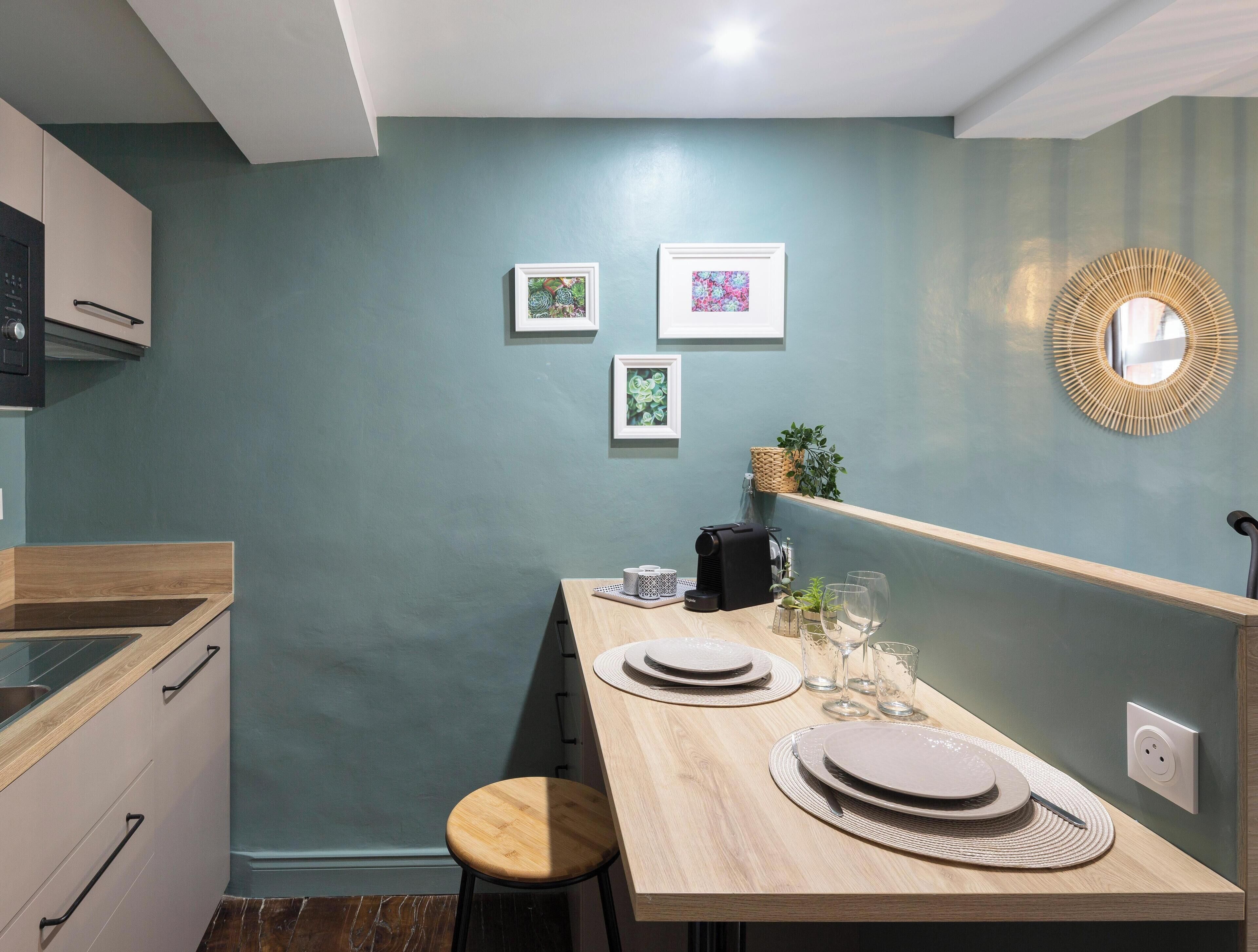 Una cocina moderna con encimera de madera, un fregadero y una zona de comedor con una mesa preparada para dos.