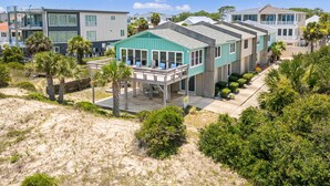 A coastal hotel with a covered outdoor seating area, multiple-story buildings, and a sandy landscape. - Oceanview Retreat | Just Steps from the Beach (Tybee Island)