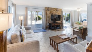A spacious living room with a stone fireplace, a television, and a sofa set. - Oceanview Retreat | Just Steps from the Beach (Tybee Island)