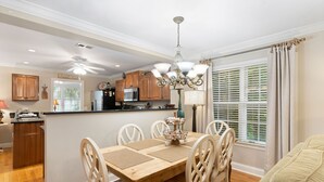 A dining area with a wooden table, white chairs, and a chandelier. - Village Walk - 3 bedrooms, 2 1/2 bathrooms located next to the Village (Saint Simons Island)