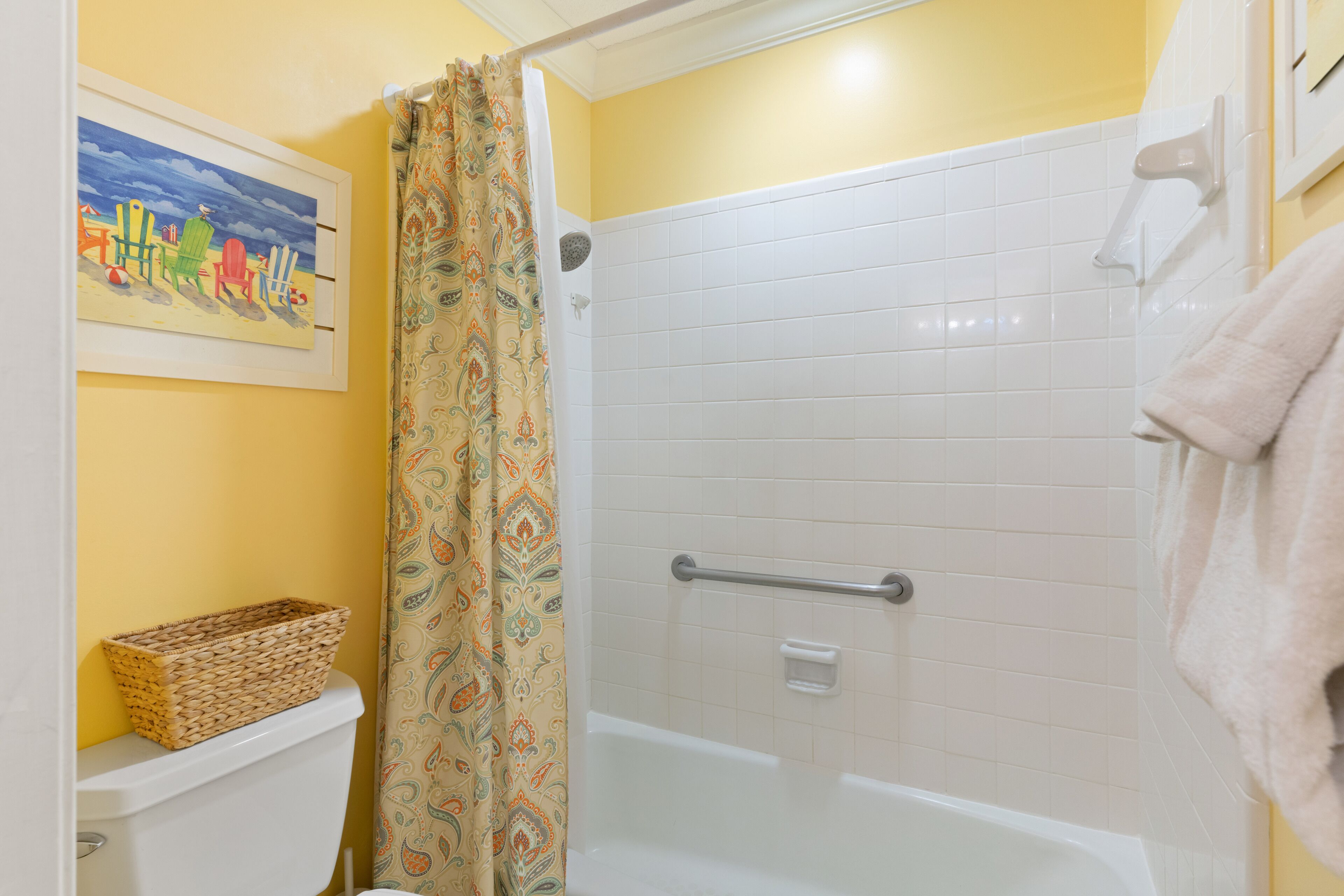 A bathroom with a shower, toilet, and a basket on the toilet.