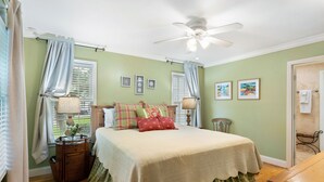A bedroom with a bed, a ceiling fan, a window with curtains, a nightstand, and wall art. - Village Walk - 3 bedrooms, 2 1/2 bathrooms located next to the Village (Saint Simons Island)