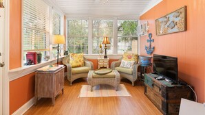 A cozy room with two wicker chairs, a small table, and a television on a wooden chest. - Village Walk - 3 bedrooms, 2 1/2 bathrooms located next to the Village (Saint Simons Island)