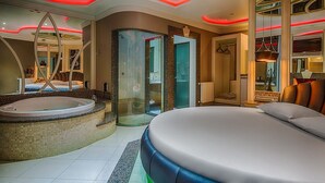Ein modernes Hotelzimmer mit einem großen Bett, einer Whirlwanne und einem gläsernen Duschbereich.