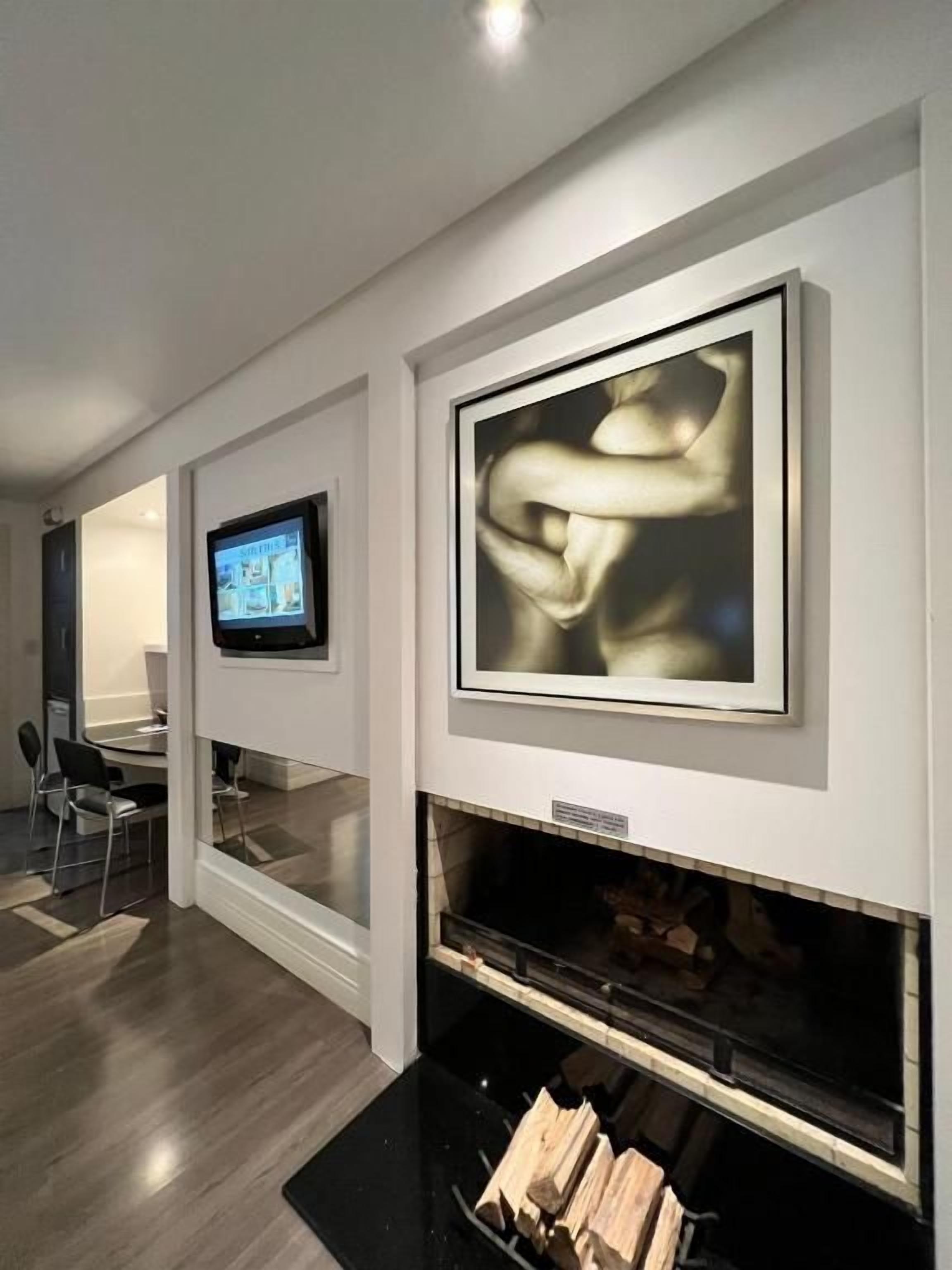 Um interior moderno com lareira, obras de arte emolduradas e uma televisão.