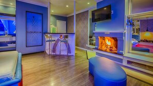 Ein modernes Wohnzimmer mit Kamin, Wandfernseher und Barbereich.
