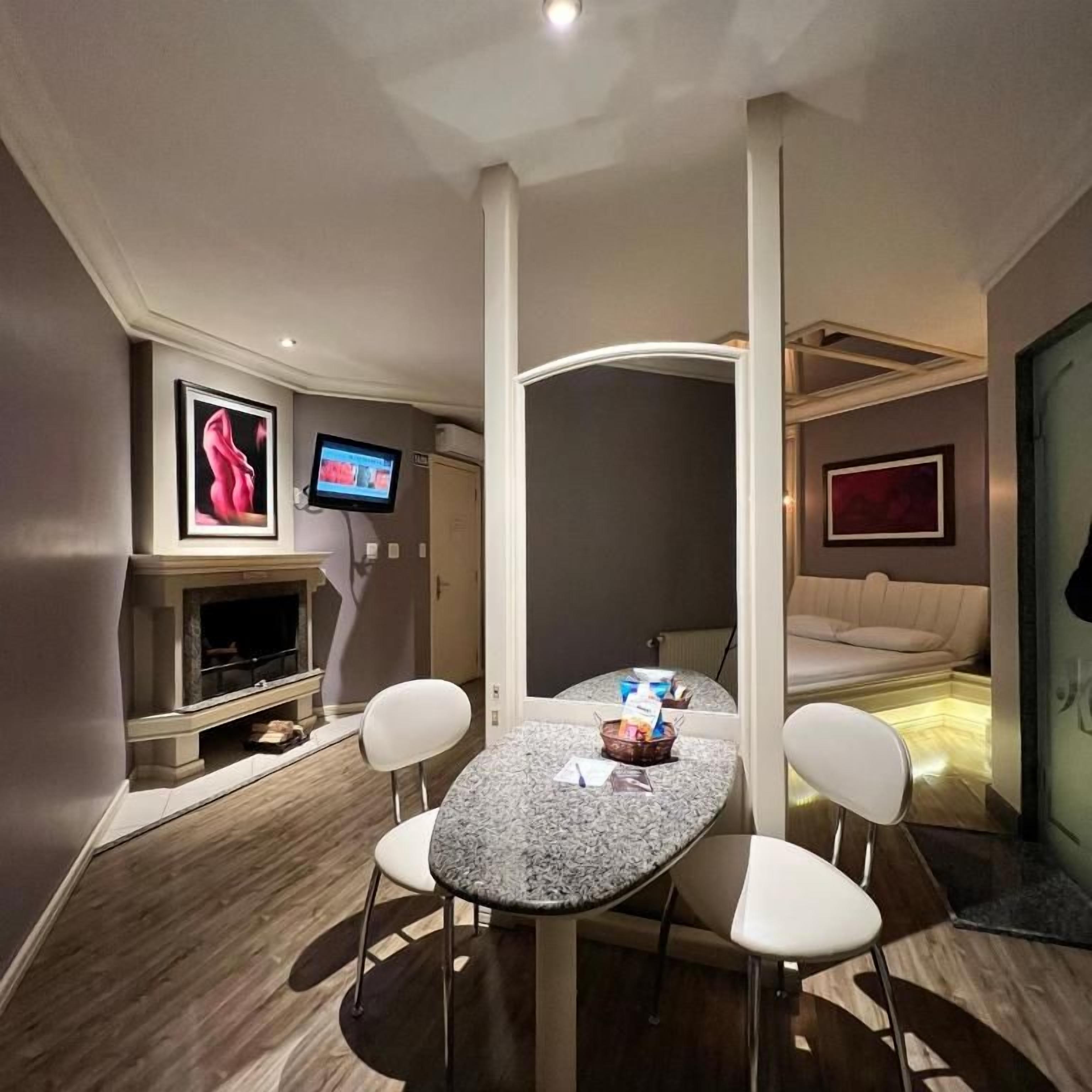 Habitación de hotel compacta con comedor, televisor, chimenea y cama.