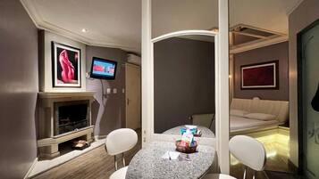 Habitación de hotel compacta con comedor, televisor, chimenea y cama.