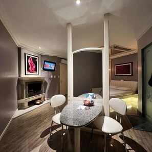A compact hotel room with a dining area, a television, a fireplace, and a bed. - Ettus Motel (Caxias do Sul)