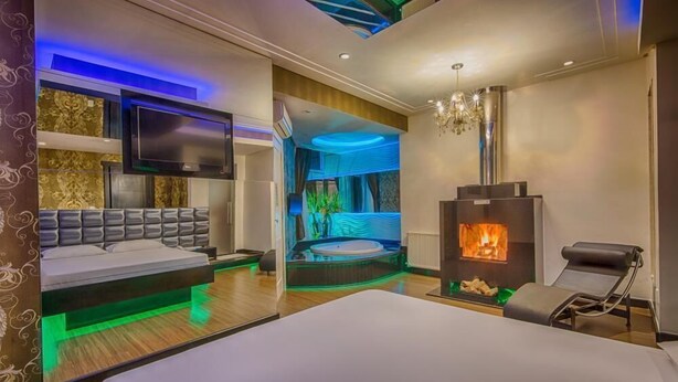 Ein modernes Hotelzimmer mit Bett, Fernseher, Kamin und Whirlpool.