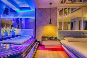 Un dormitorio moderno con una cama grande, una mesita de noche pequeña y una bañera integrada.