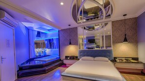 Ein modernes Schlafzimmer mit einem großen Bett, einem integrierten Fernseher und einem einzigartigen, runden Deckenstil.