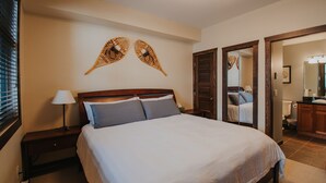 Una habitación de hotel con una cama grande, una mesita de noche, una lámpara y un espejo.