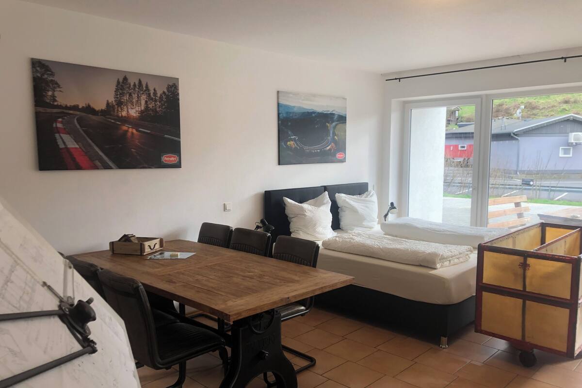Una habitación con una cama, una mesa y un ventanal.
