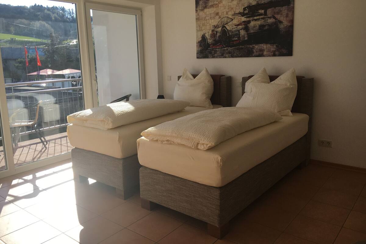 Un dormitorio con dos camas, un ventanal grande y un cuadro en la pared.