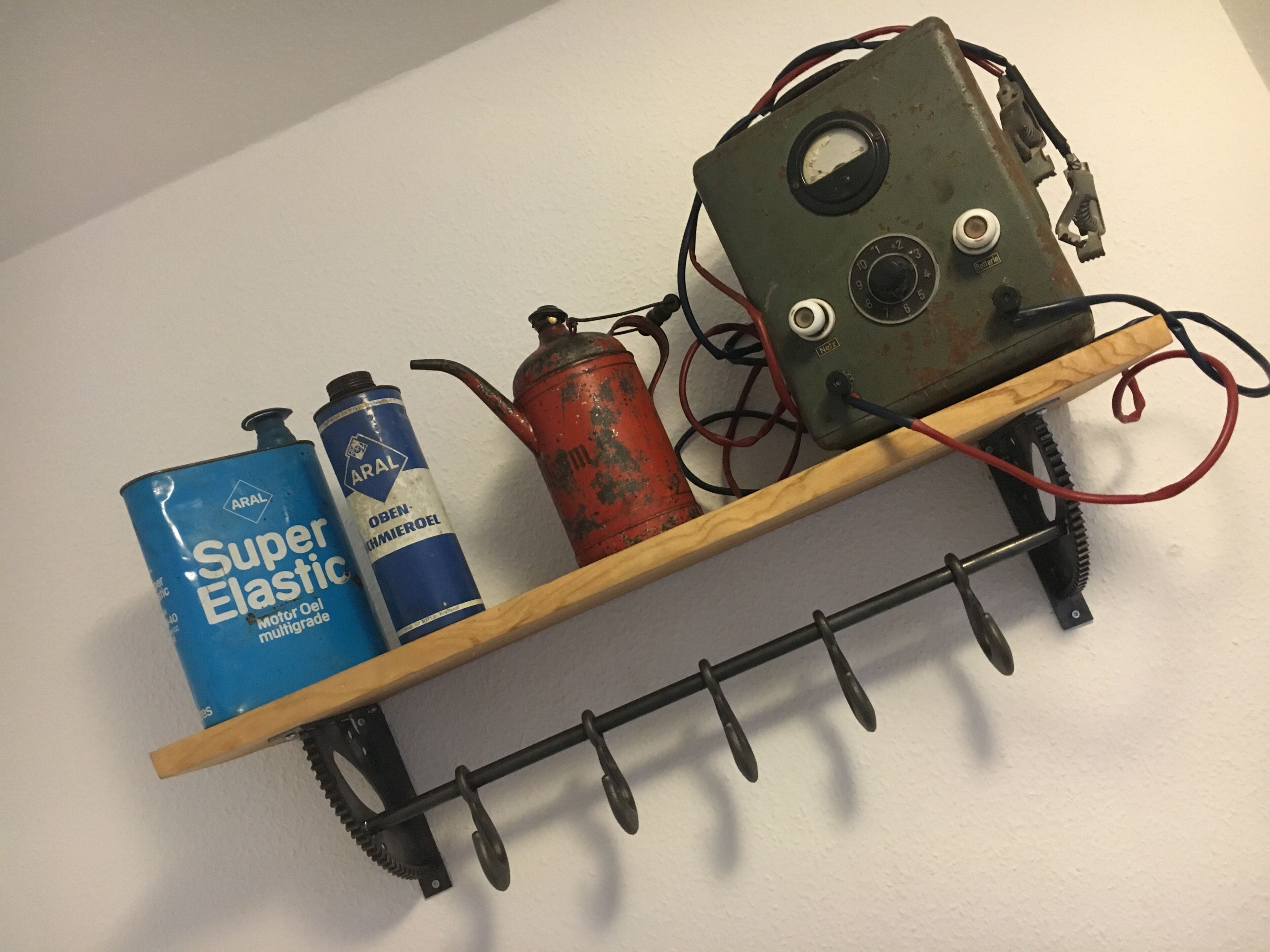 A shelf with two cans of Super Elastic motor oil and a rusted metal object with wires.