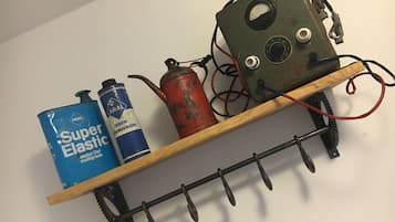 A shelf with two cans of Super Elastic motor oil and a rusted metal object with wires.
