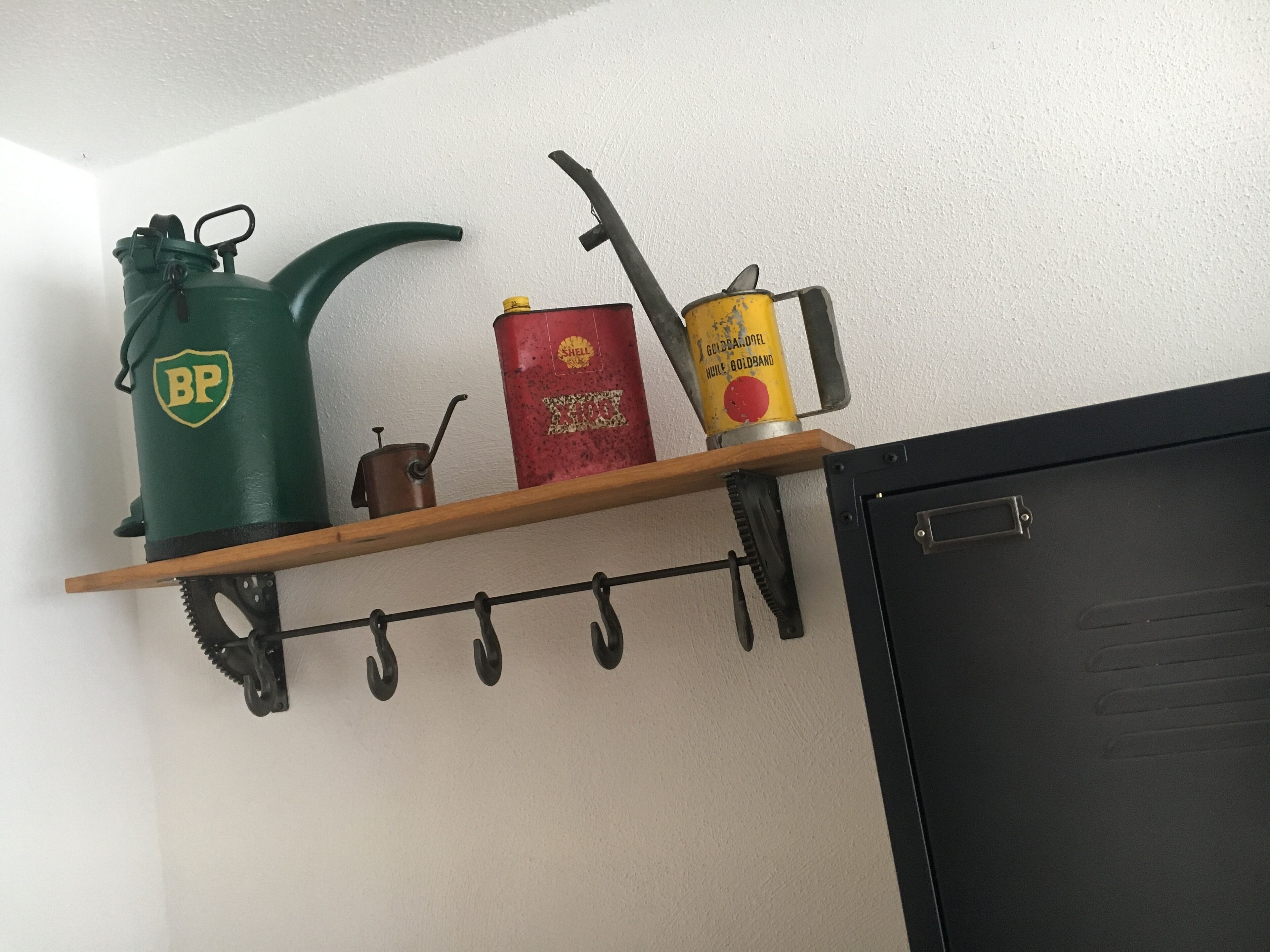 Una estantería con una jarra de agua verde, una lata roja y un bote amarillo.