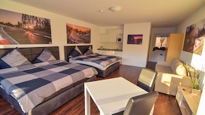 A modern hotel room with two beds, a small dining area, and a kitchenette. - Nringrooms Exit-Breidscheid (Adenau)