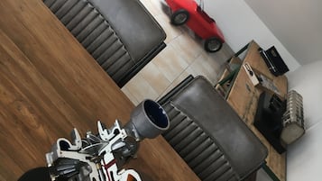 Een eetgedeelte met een houten tafel, zwarte leren stoelen en een rode kinderauto op de vloer.