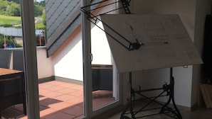 A room with a large window, a ceiling fan, and a drafting table with a drawing. - Nringrooms Exit-Breidscheid (Adenau)