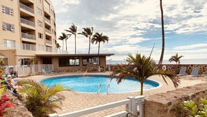 A swimming pool with lounge chairs and palm trees, surrounded by a building with balconies. - Amazing Ocean/Beach Front, Pool Side, Ground Floor Remodeled 2 Bdr 2 Bath Condo  (Kihei)