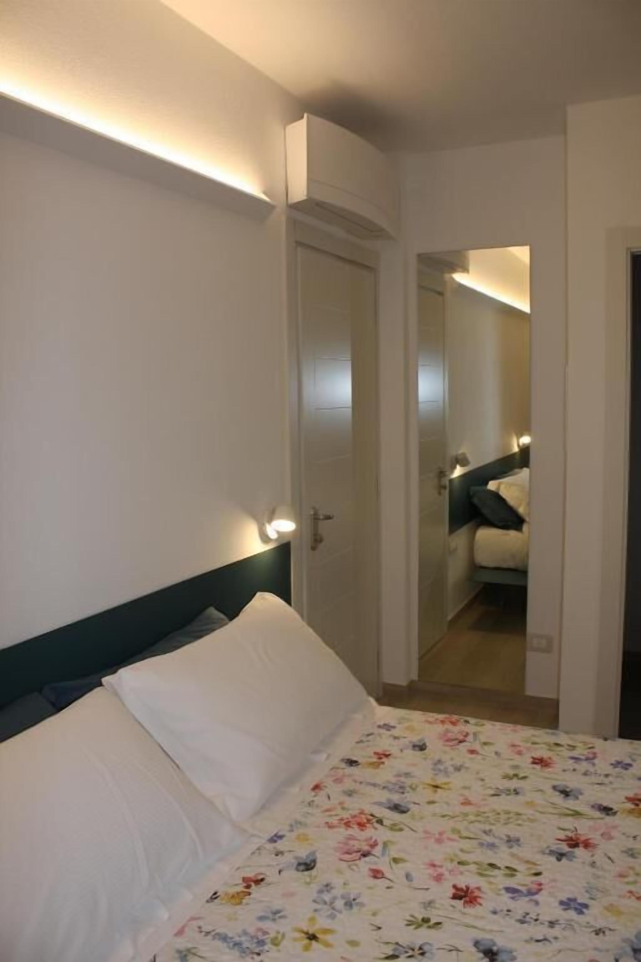 Una habitación de hotel con cama, mesita de noche y espejo.