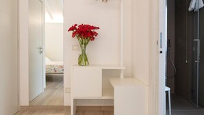Een moderne badkamer met een witte wastafel, een hangende handdoekhouder en een vaas rode bloemen.