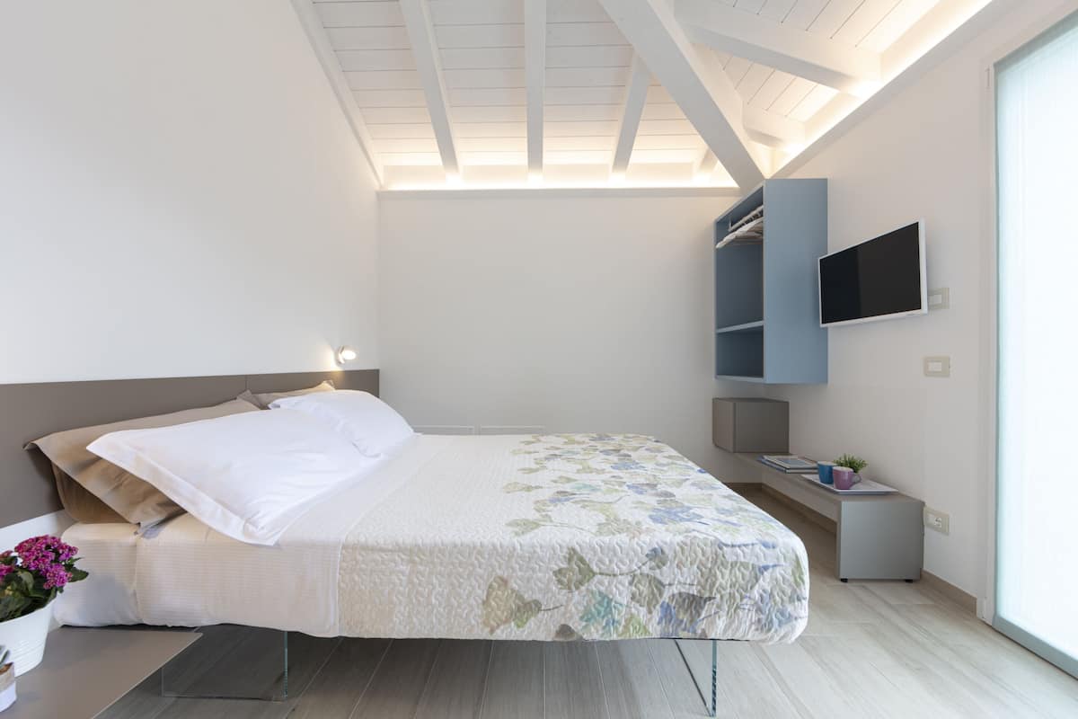 Une chambre à coucher avec un lit, un bureau, une télévision et une fenêtre.