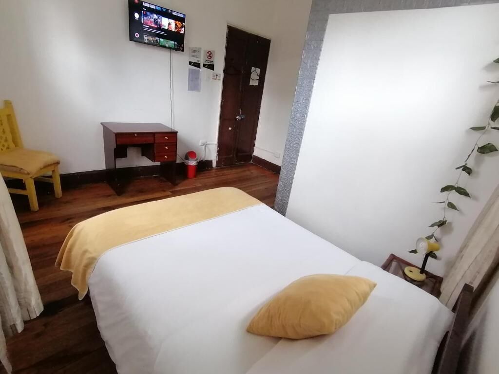 Une chambre à coucher avec un lit, un bureau, une chaise et un téléviseur.