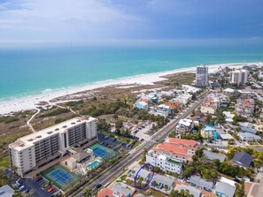 An aerial view of a coastal town with a beach, a large hotel with multiple floors, and a road running through the center. - Cottage Across The Street From #1 Beach (Siesta Key)