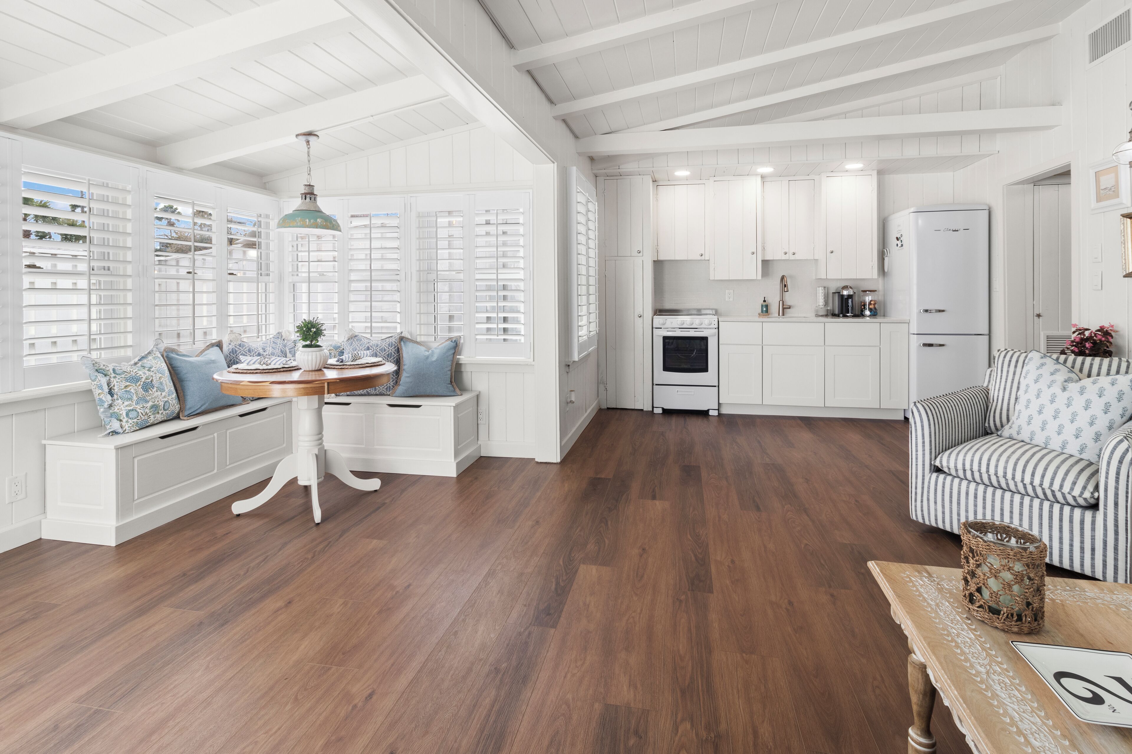 A spacious kitchen with white cabinetry, a dining area with a round table, and a cozy seating area with a striped sofa.