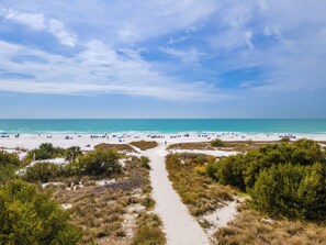 A beach with a sandy path leading to the water, surrounded by greenery. - Cottage Across The Street From #1 Beach (Siesta Key)