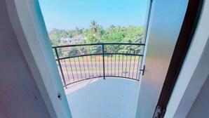 A balcony with a metal railing, a clear view of a road, and greenery in the background. - Rachana Palace (Mangaluru)