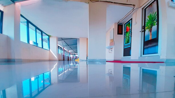 A spacious, well-lit corridor with reflective flooring, large windows, and a clean, modern design. - Rachana Palace (Mangaluru)