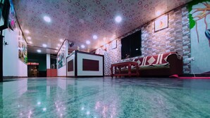 A spacious lobby with a polished floor, a reception desk, a sofa, and a wall with a patterned design. - Rachana Palace (Mangaluru)