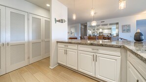 Cocina amplia con armarios blancos, encimera de granito e iluminación colgante.