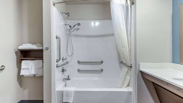 A modern bathroom with a walk-in shower, grab bars, and a towel rack.