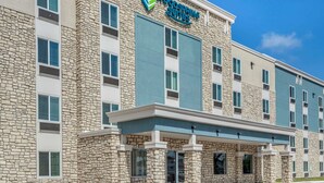 Un hotel con fachada de piedra, varias ventanas y un letrero que dice "Woodspring Suites".