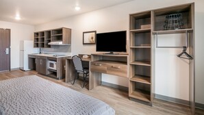Un dormitorio moderno con cama, escritorio con ordenador, silla y estanterías empotradas.