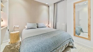 A bedroom with a bed, bedside table, and a large mirror. - Apartamentos Madrid Rio (Madrid)