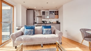 A modern living space with a sofa, remote control, and a dining area. - Modern Leeds City Apartment (Leeds)