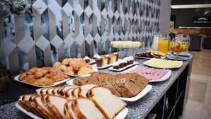 Un buffet proposant une variété de plats, notamment du pain, des pâtisseries et une salade de fruits.