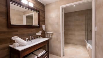 A modern bathroom with a wooden vanity, a large mirror, and a glass shower enclosure.