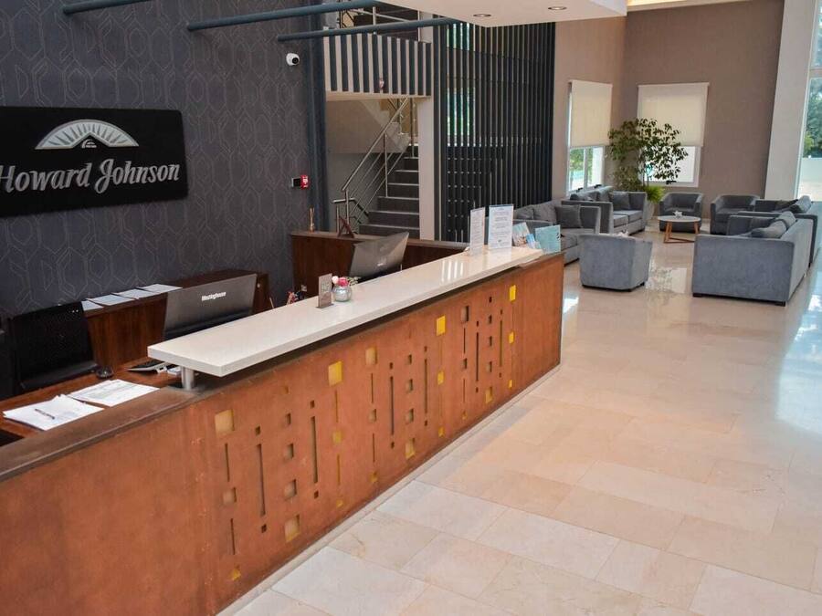 A reception area with a wooden reception desk, a staircase, and a seating area with sofas.