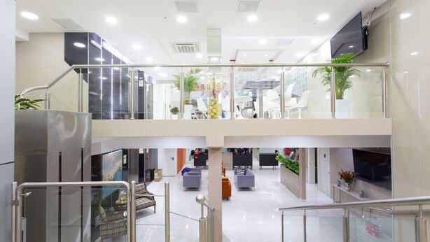 Un espace intérieur à plusieurs niveaux, doté de rampes en verre, de coins salon et d’un escalier.
